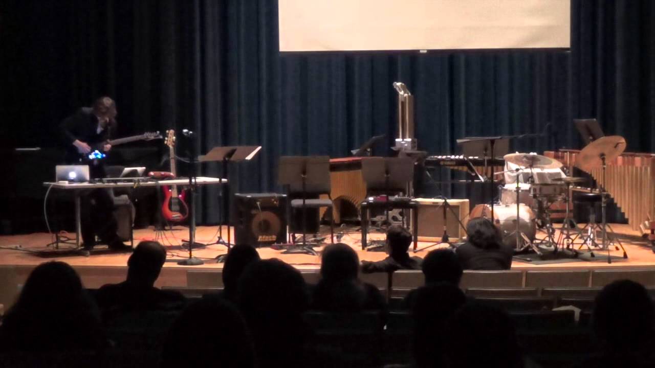 Alec Trumble performing with guitar, controllers, and computer on a recital stage